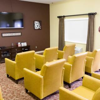 A cozy room with yellow chairs arranged facing a television, ideal for meetings or small gatherings.
