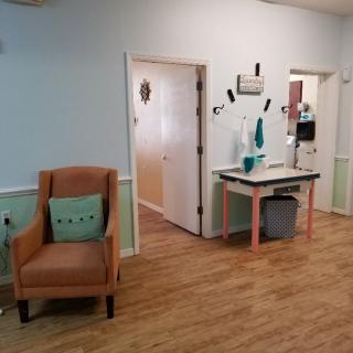 A cozy waiting area with a comfortable chair and a small table against light blue painted walls.