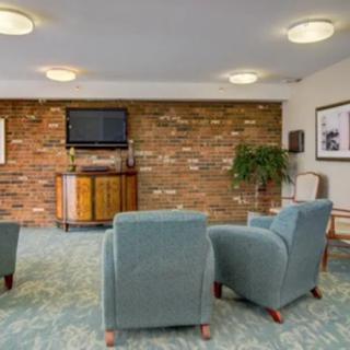 A cozy living room with blue armchairs facing a brick wall and a TV.