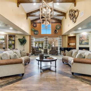 A spacious and elegantly designed living room featuring comfortable sofas, wooden beams, and a chandelier.