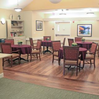 A cozy dining area with multiple tables and chairs, featuring wood flooring and wall decorations.