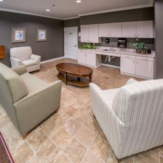 A cozy living area with armchairs, a sofa, and a kitchenette.