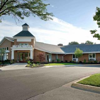 A large brick building with an entrance canopy and landscaped surroundings.