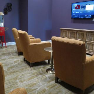 A modern lounge area with comfortable chairs and a wall-mounted television.
