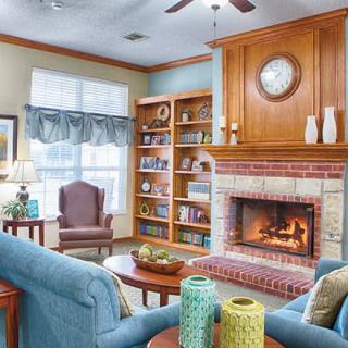 A cozy living room featuring a fireplace, bookshelves, and comfortable seating.