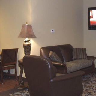 A cozy living room featuring a sofa, chair, lamp, and television.