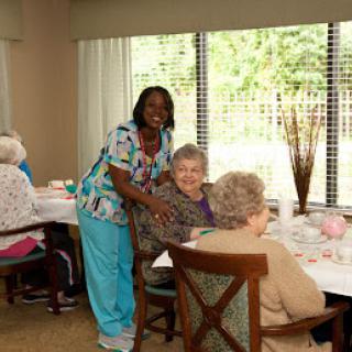 A caregiver interacting with elderly residents during a dining activity.
