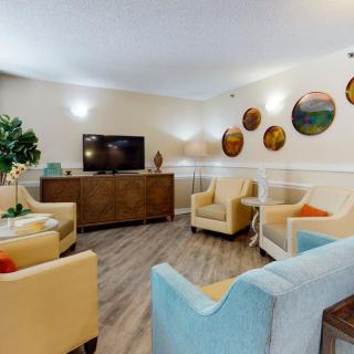 A cozy living room with comfortable seating, a TV, and decorative wall accents.