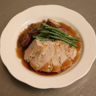 A delicious serving of sliced pork with green beans and roasted potatoes, drizzled in savory gravy.