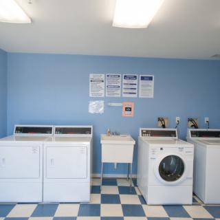 A laundry room with two dryers and two washing machines against a blue wall.