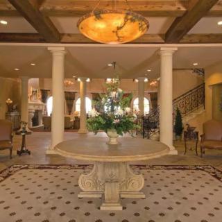 A luxurious foyer with elegant decor, featuring a central table and chandelier.