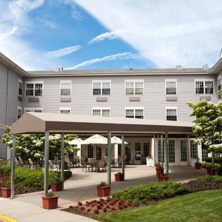A residential building with outdoor seating and well-maintained landscaping on a sunny day.