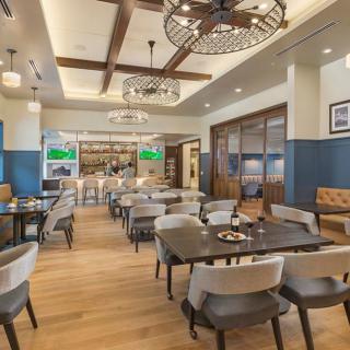 A cozy restaurant interior featuring a spacious dining area with modern decor and wooden flooring.