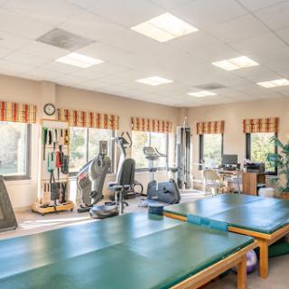 A well-equipped physical therapy room featuring treatment tables and various exercise machines.