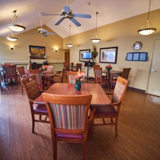 An inviting dining area featuring wooden tables and chairs, with warm lighting and a ceiling fan.