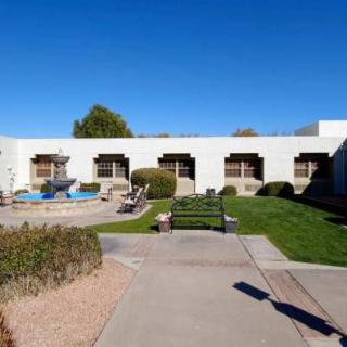 A landscaped courtyard with benches, a fountain, and a modern building under a clear blue sky.