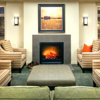 A cozy living room with a central fireplace, surrounded by comfortable seating and warm lighting.