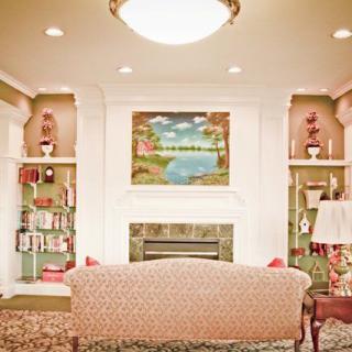 A cozy living room featuring a fireplace with built-in bookshelves and a sofa facing an artwork above the mantel.