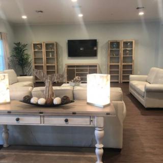 A modern living room with neutral colors featuring sofas, shelves, and decorative lamps.