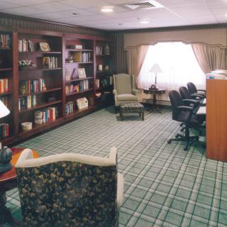 A cozy library-style meeting room with bookshelves and comfortable seating.