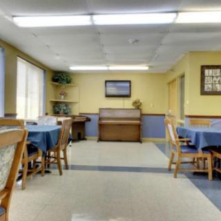 An indoor dining area with several tables and chairs, featuring a piano against the wall.