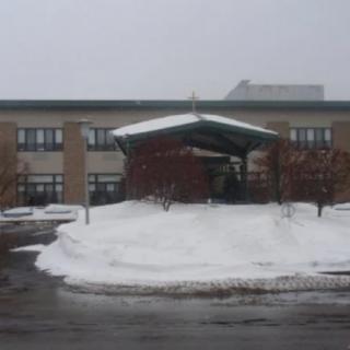 A building entrance surrounded by snowy grounds on an overcast day.