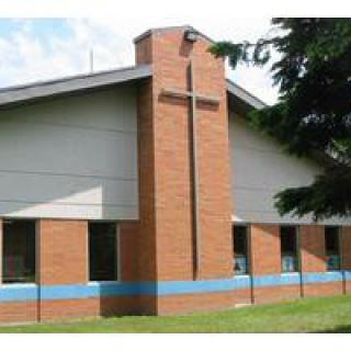 A small brick church with a prominent cross symbol on its facade.