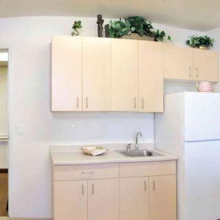 A minimalist kitchen setup with light-colored cabinets, a sink, and a white refrigerator.