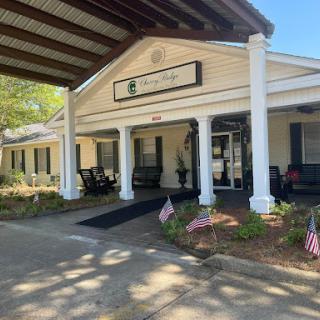 A welcoming entrance to a residential building with rocking chairs on the porch and decorative landscaping.