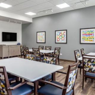 A modern meeting room with tables, chairs, artistic decor, and a TV on the wall.
