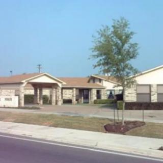 A suburban residential house with a tree in the front yard and a road running alongside.