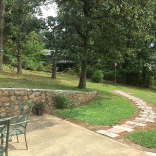 A serene outdoor garden with a stone pathway leading through lush greenery and trees.