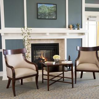 A cozy modern living room with two armchairs by a fireplace and a small table.
