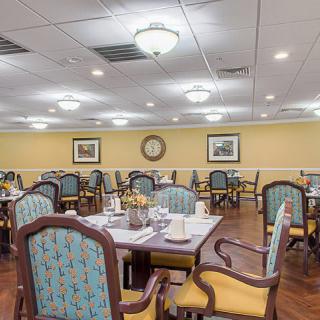 A well-lit dining room with neatly arranged tables and chairs, featuring elegant decor.