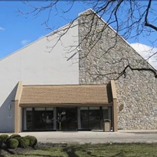 A church building with a stone facade and pointed roof under a clear blue sky.