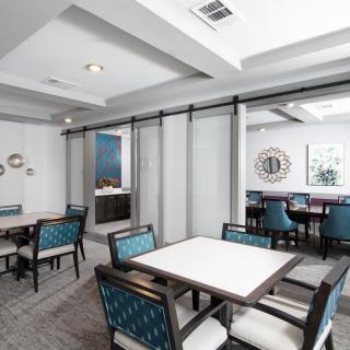 A modern dining area with tables and chairs, featuring a sliding glass partition and stylish decor.