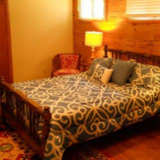 A cozy bedroom with a patterned bedspread, wooden furniture, and warm lighting.