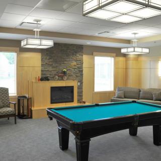A cozy recreation room featuring a pool table, fireplace, and modern lighting fixtures.