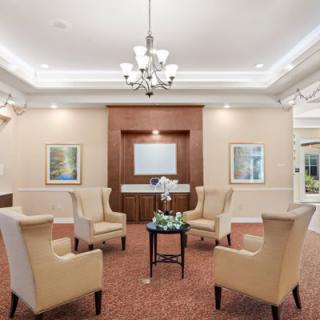 A cozy living room setup with armchairs arranged in a circle around a small table, illuminated by a chandelier.