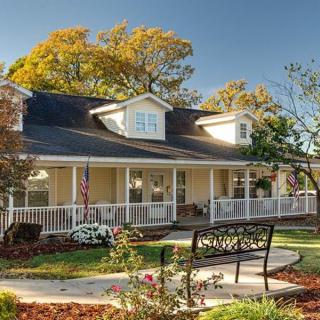 A charming house with a wraparound porch and well-maintained garden.