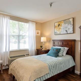 A cozy bedroom with a single bed, large window, and decorative artwork on the wall.
