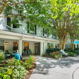 A charming residential building surrounded by lush landscaping and a winding pathway.
