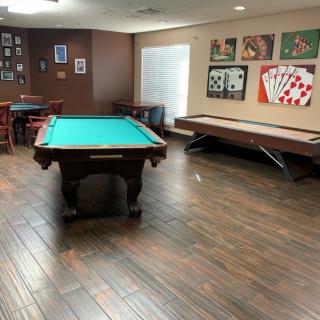 A well-equipped game room featuring a pool table and shuffleboard, adorned with card-themed artwork.