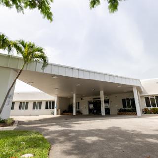 A modern building featuring a covered entrance and lush palm trees.