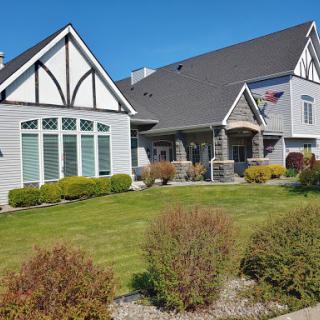 A beautiful modern house with a well-maintained lawn and clear blue skies.