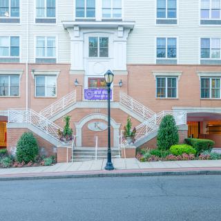 A residential apartment building with a prominent staircase entrance and well-maintained landscaping.