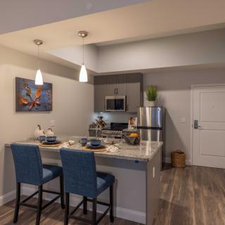 A modern kitchen with an open concept, featuring bar stools and pendant lighting.
