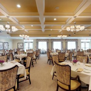 An elegant dining room with neatly arranged tables and grand chandeliers.