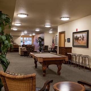 A cozy lounge area featuring a pool table, comfortable seating, and decorative artwork.