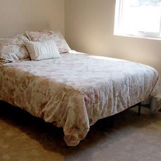 A neatly made bed in a cozy bedroom with natural light from a window.
